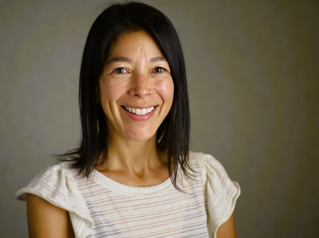 Jen smiling in professional headshot before warm dark background