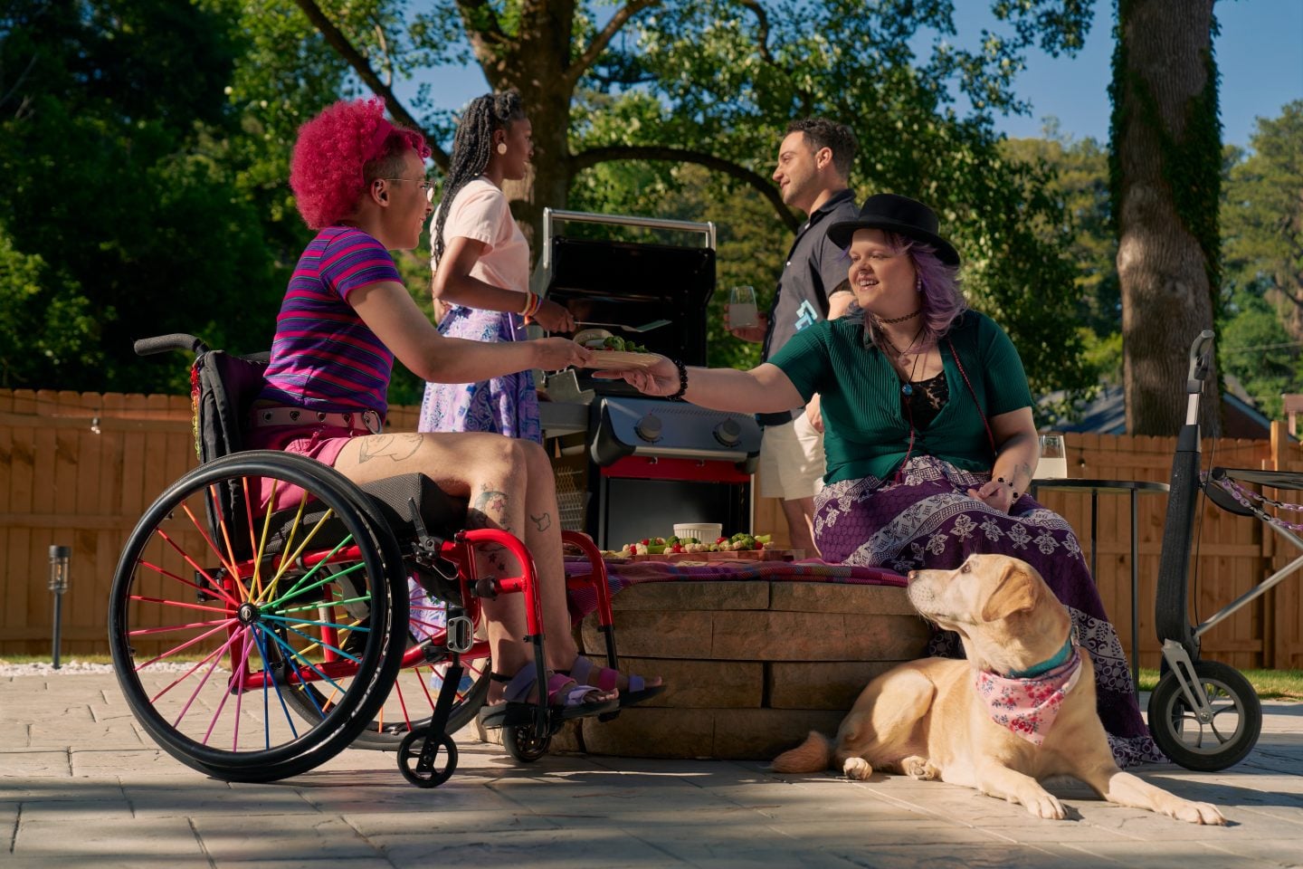 Person in wheelchair chatting with person with service dog at a barbecue
