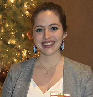 Danielle stands smiling before a lighted tree