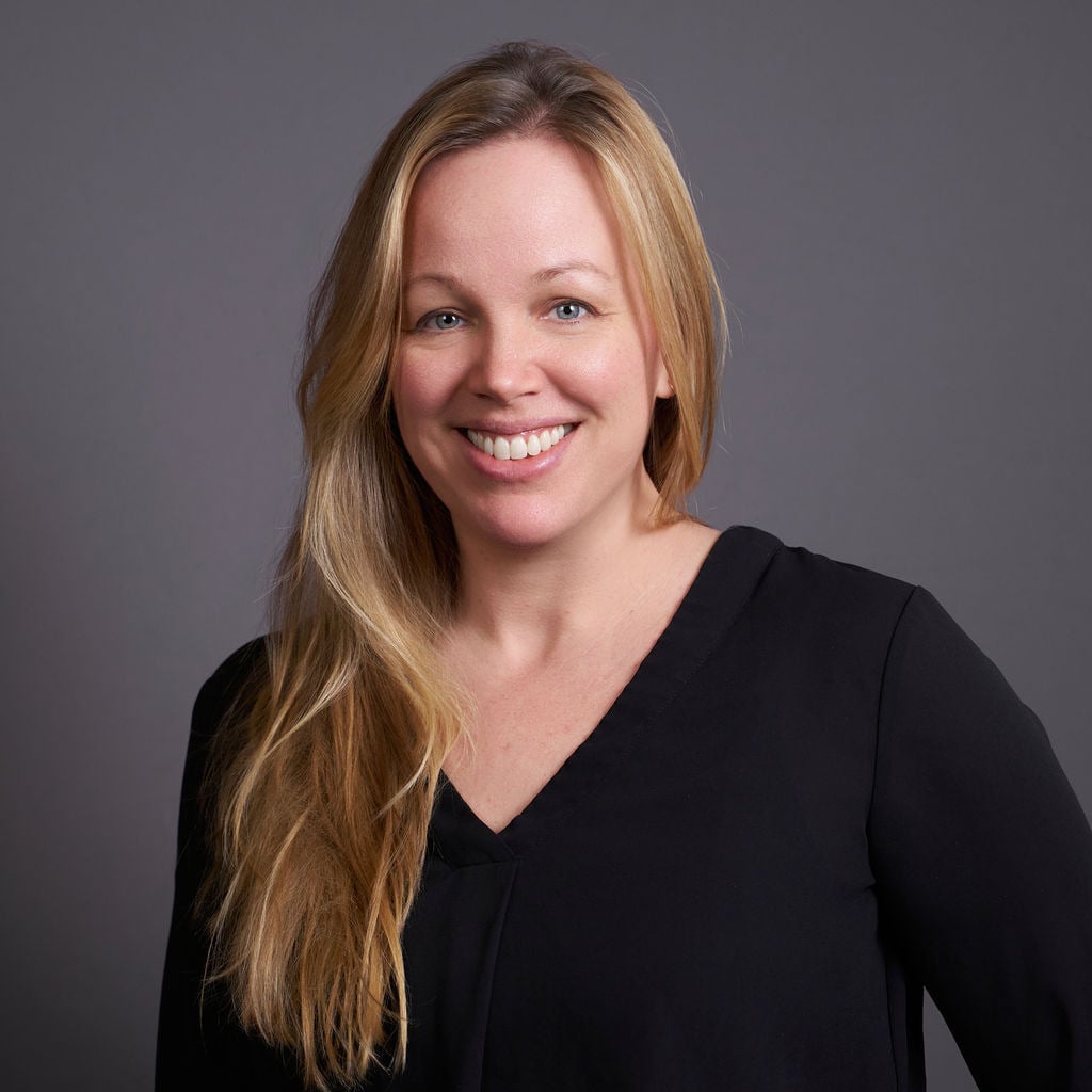 Eva in black shirt smiling against gray studio background