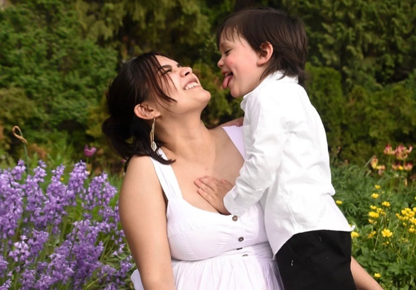 Kalaya a her young child lovingly grin at each other in a beautiful wild flower path